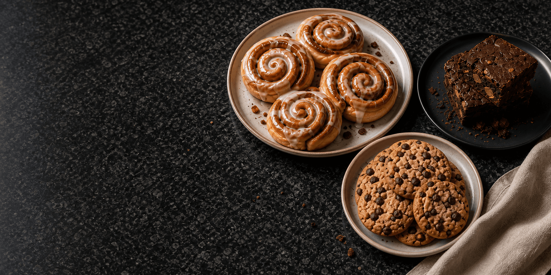Cinnamon rolls, brownies, and cookies on polished black granite